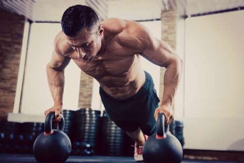 Man doing pushups off kettlebells