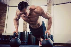 Man doing pushups off kettlebells