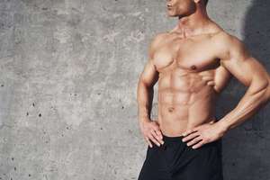Physically fit man standing against wall